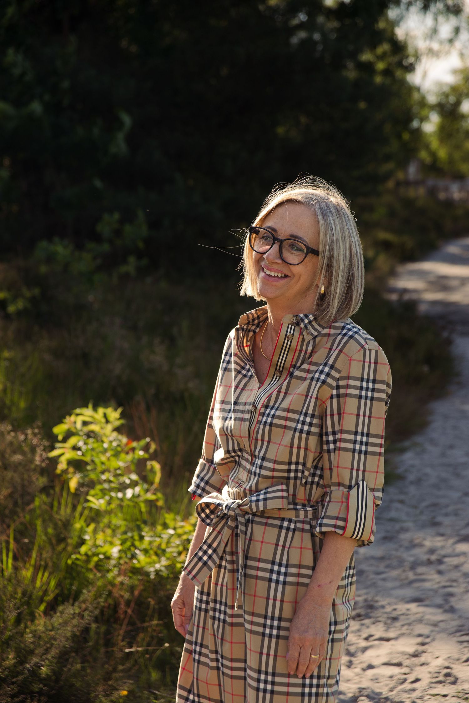 Middle aged woman standing in nature and smiling. In de Teut in Zonhoven.