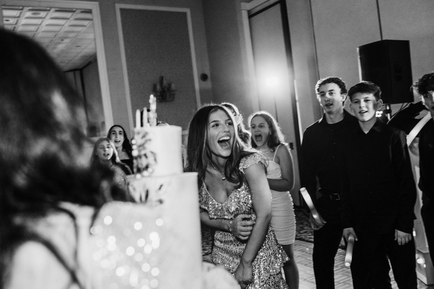 Black and white photo of people dancing and celebrating at a party with joyful expressions.