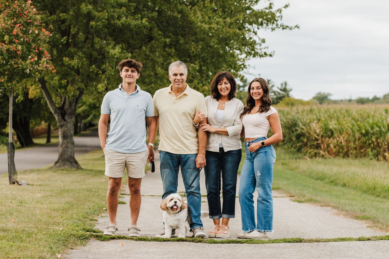 A group walks together on a tree-lined path during a sunny outdoor photo session.