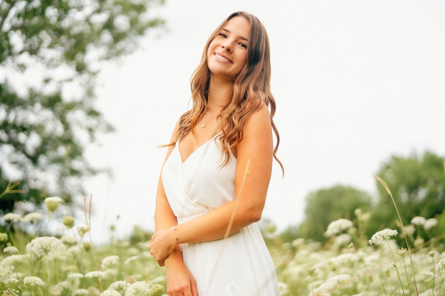 Summer portrait in white attire surrounded by blooming wildflowers.