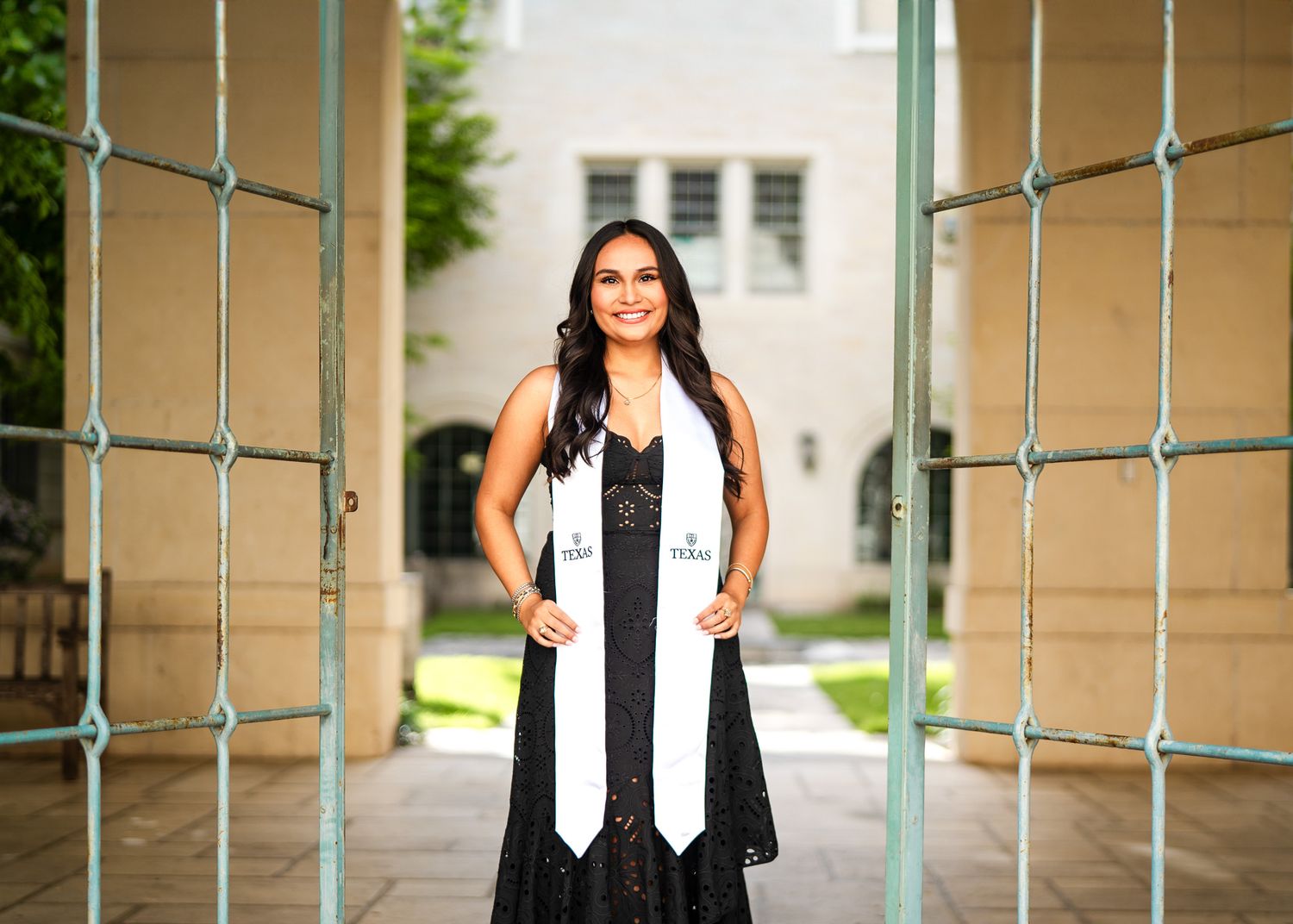 Graduates pose near turquoise railings in academic regalia during graduation photo session.