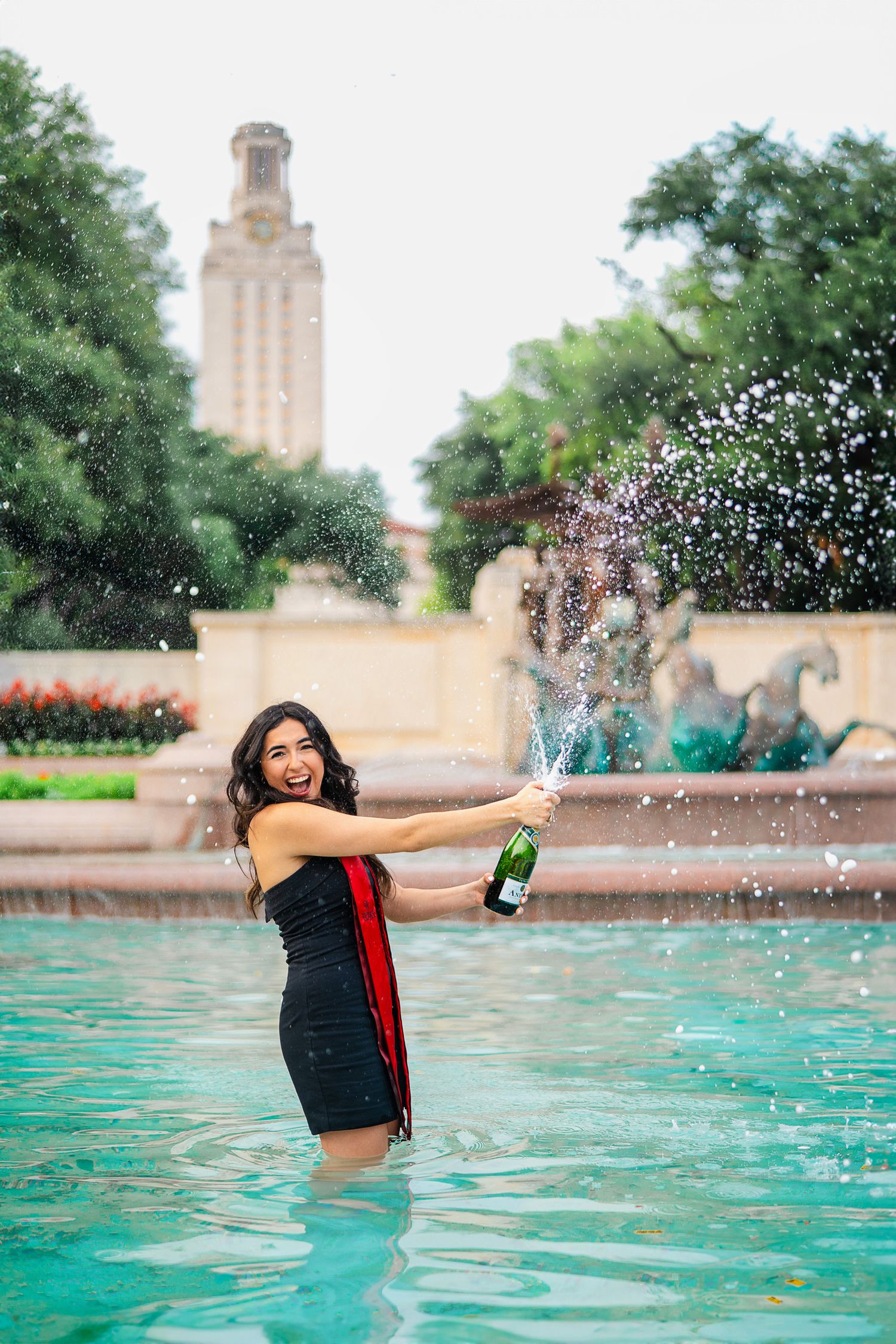 University of Texas graduation photo with champagne at campus fountain