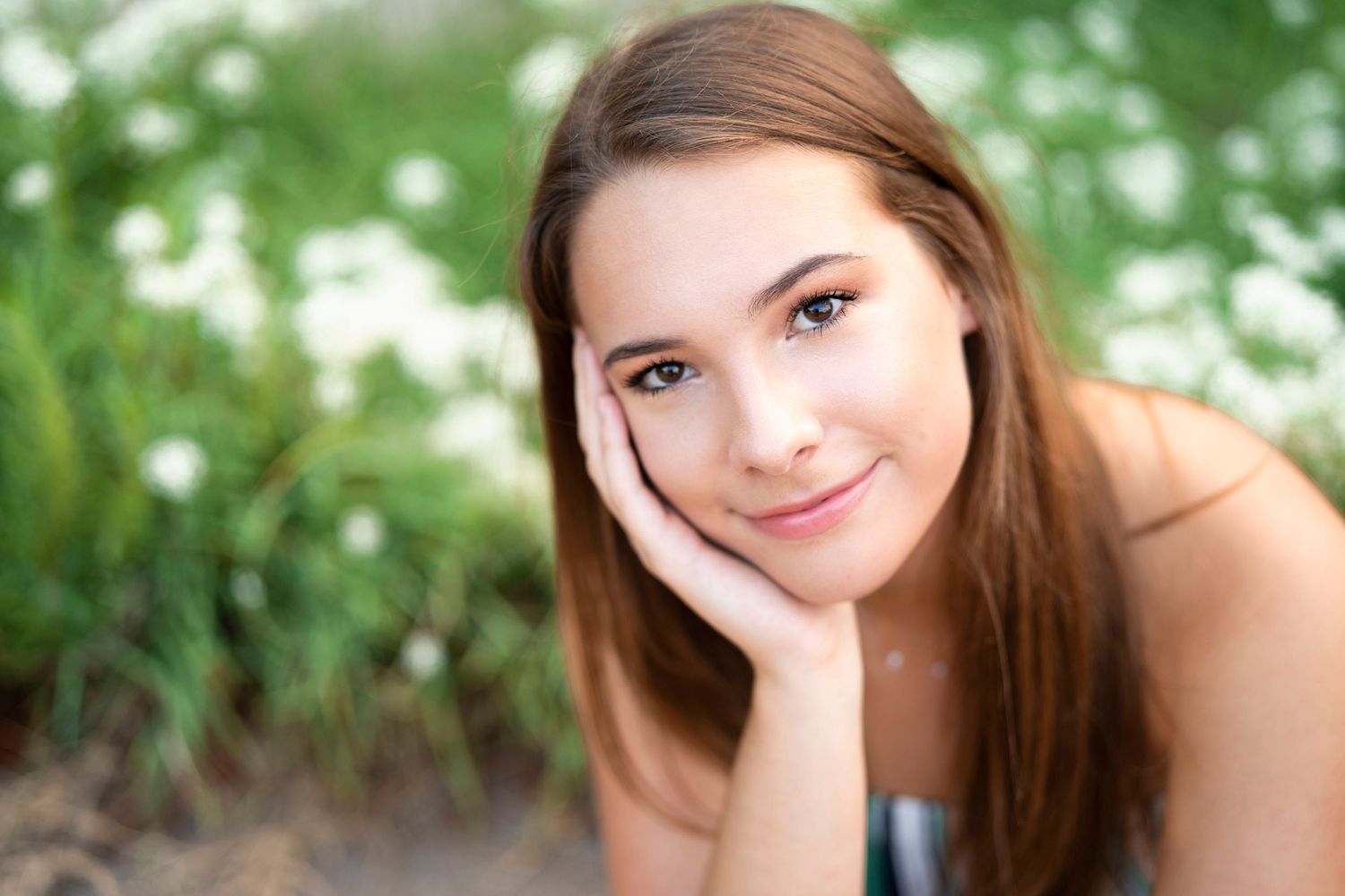 Soft focus portrait of a woman with natural makeup lying on grass.