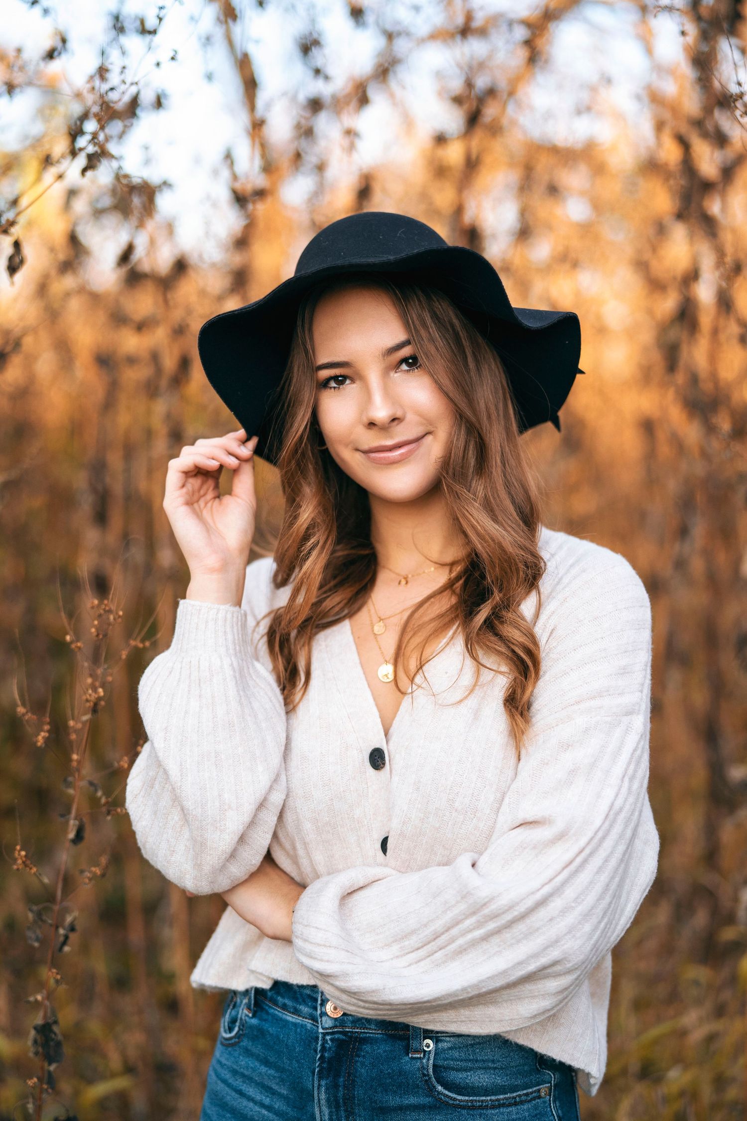 Stylish outdoor portrait with black hat, white peasant top and jeans in golden autumn light.