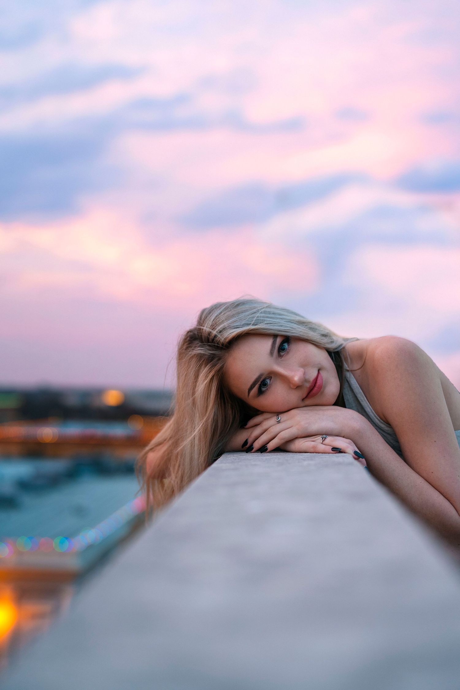 Dreamy sunset portrait of someone resting on ledge with pink sky background.