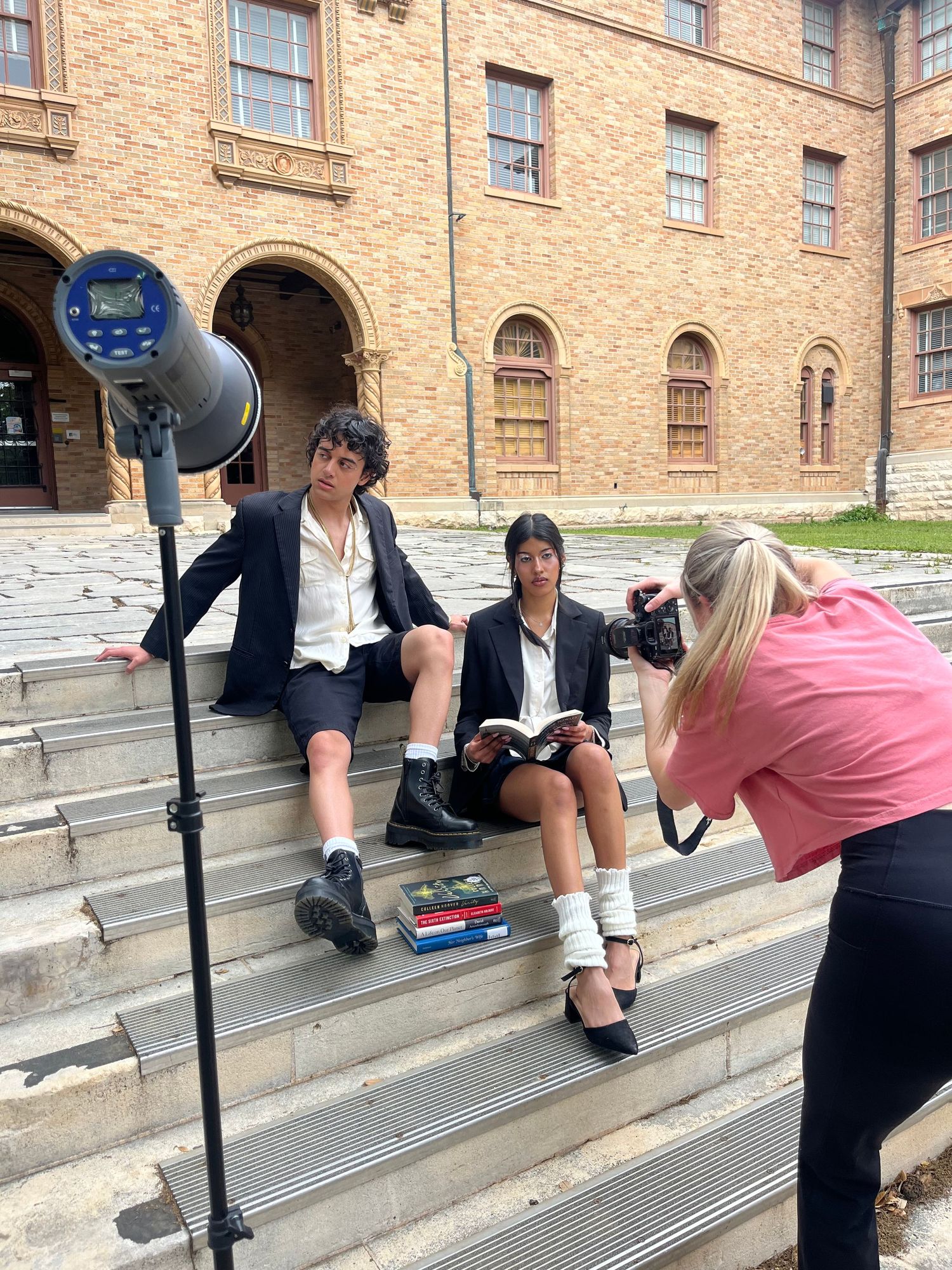 Photo shoot on brick building steps with lighting equipment and photographer.