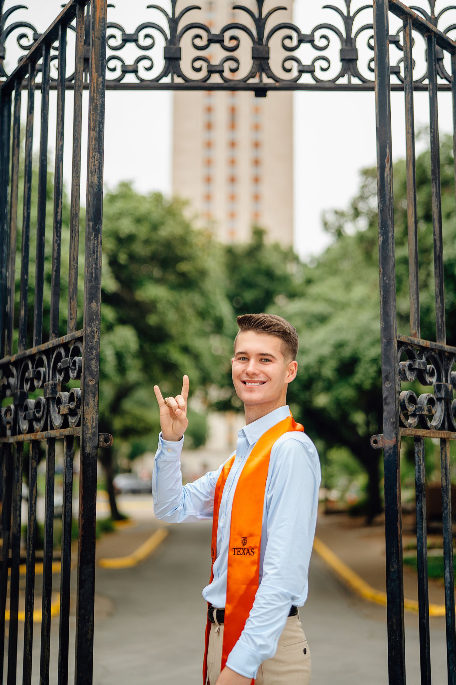 UT Austin graduation photo of male student smiling by the Tower