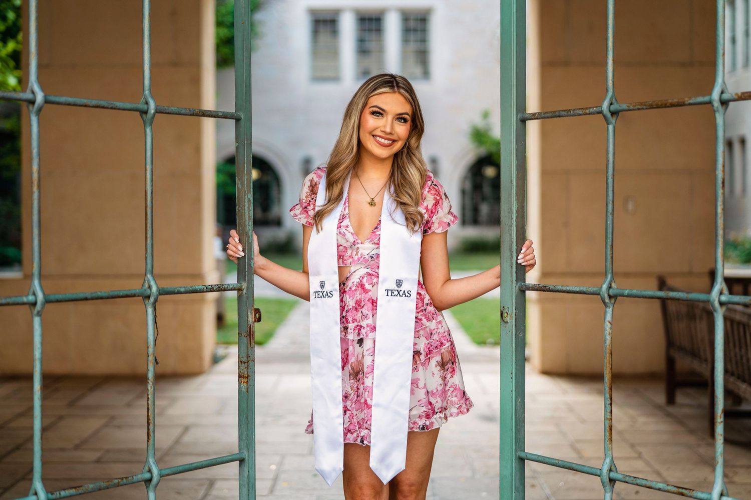 Portrait session under green archway with floral pink vest.