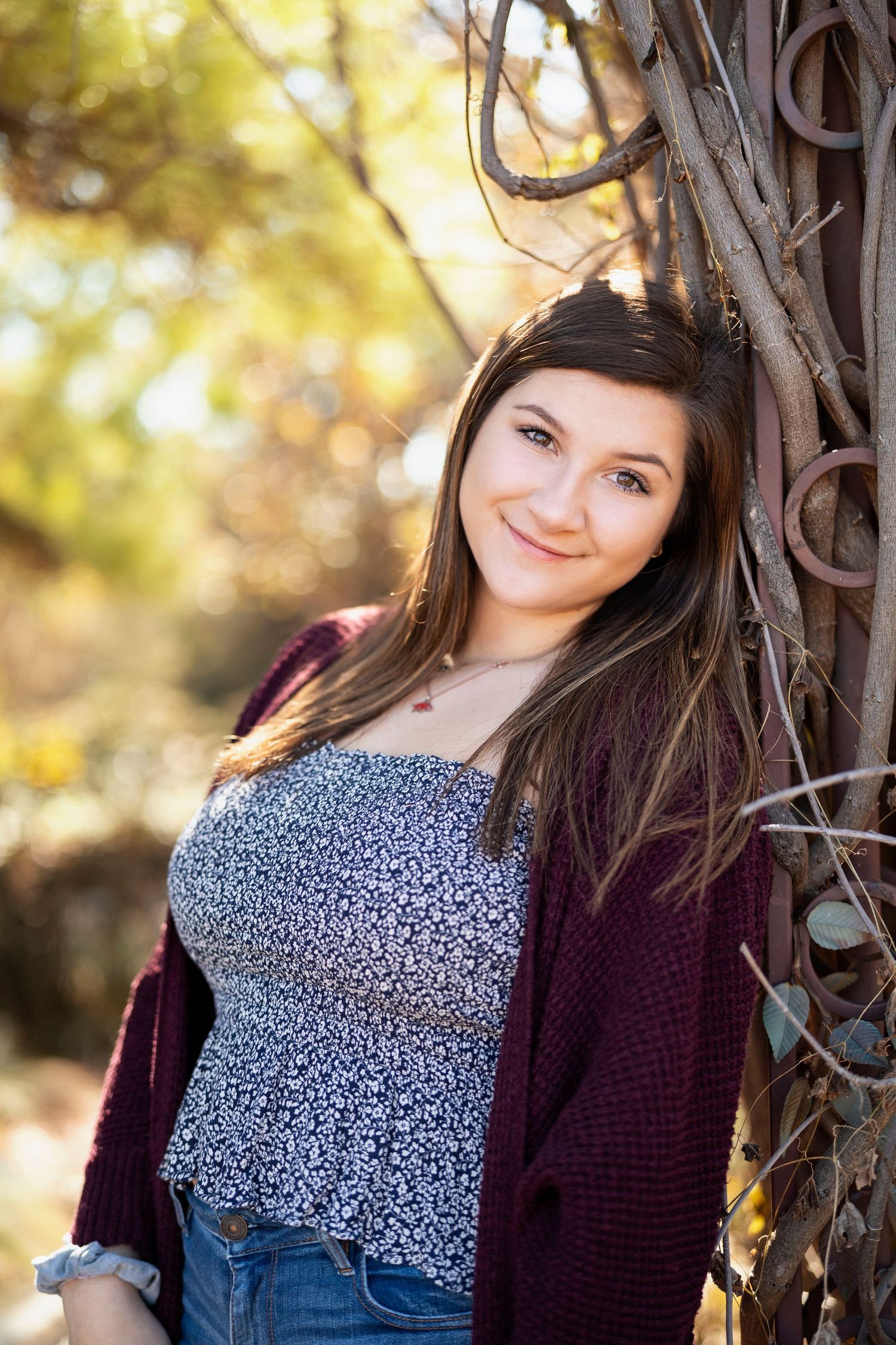 Portrait of someone in burgundy sweater leaning against decorative iron fence.