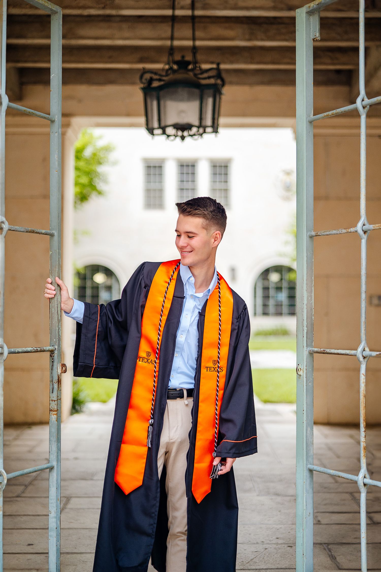UT Austin senior in cap and gown outside the Architecture building