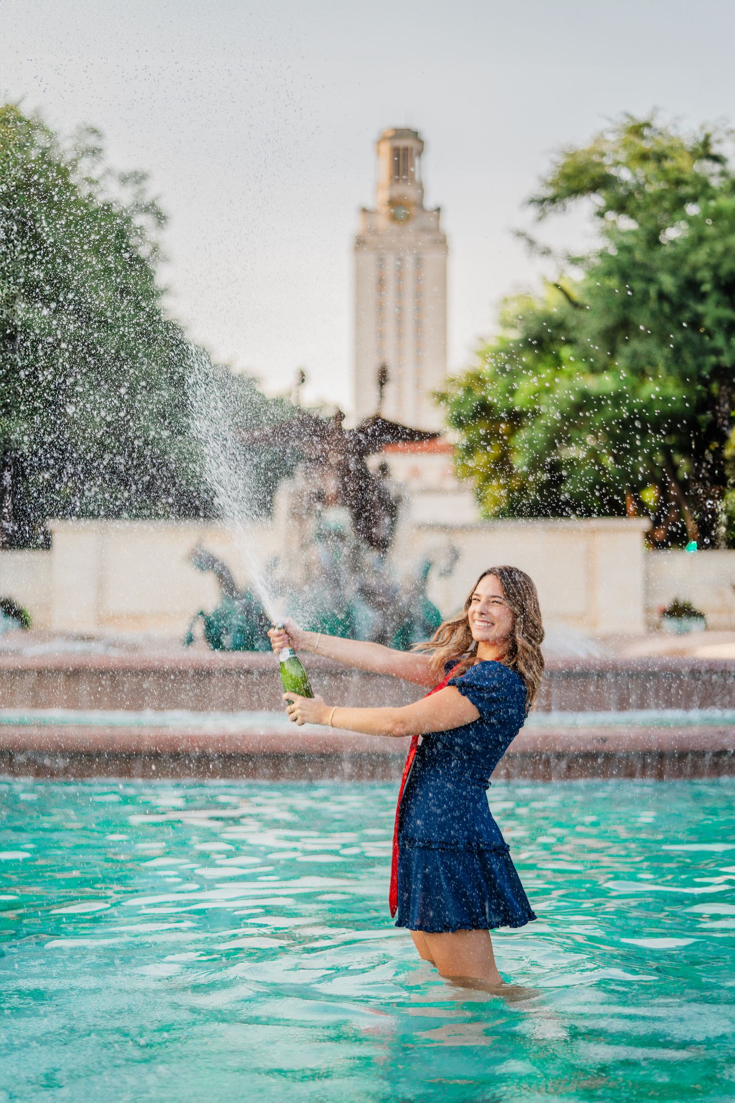 Graduation portrait with champagne pop at Littlefield Fountain, UT Austin