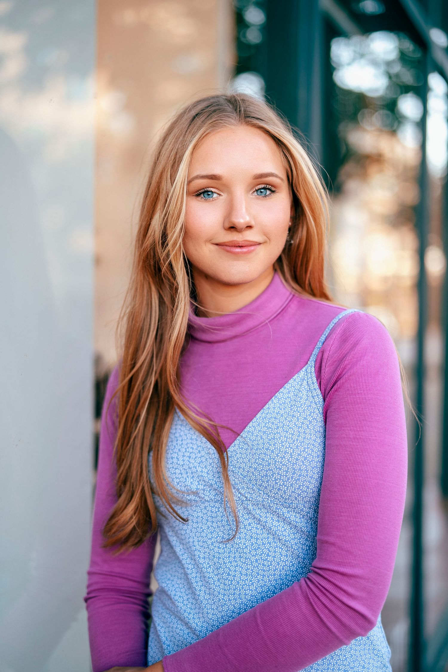 Portrait shot of a person wearing a purple turtleneck with a blue polka dot dress layered on top.