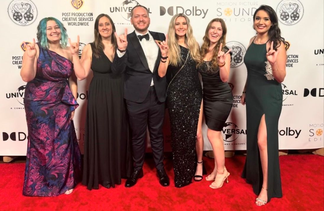 Group posing on red carpet at formal entertainment industry event.