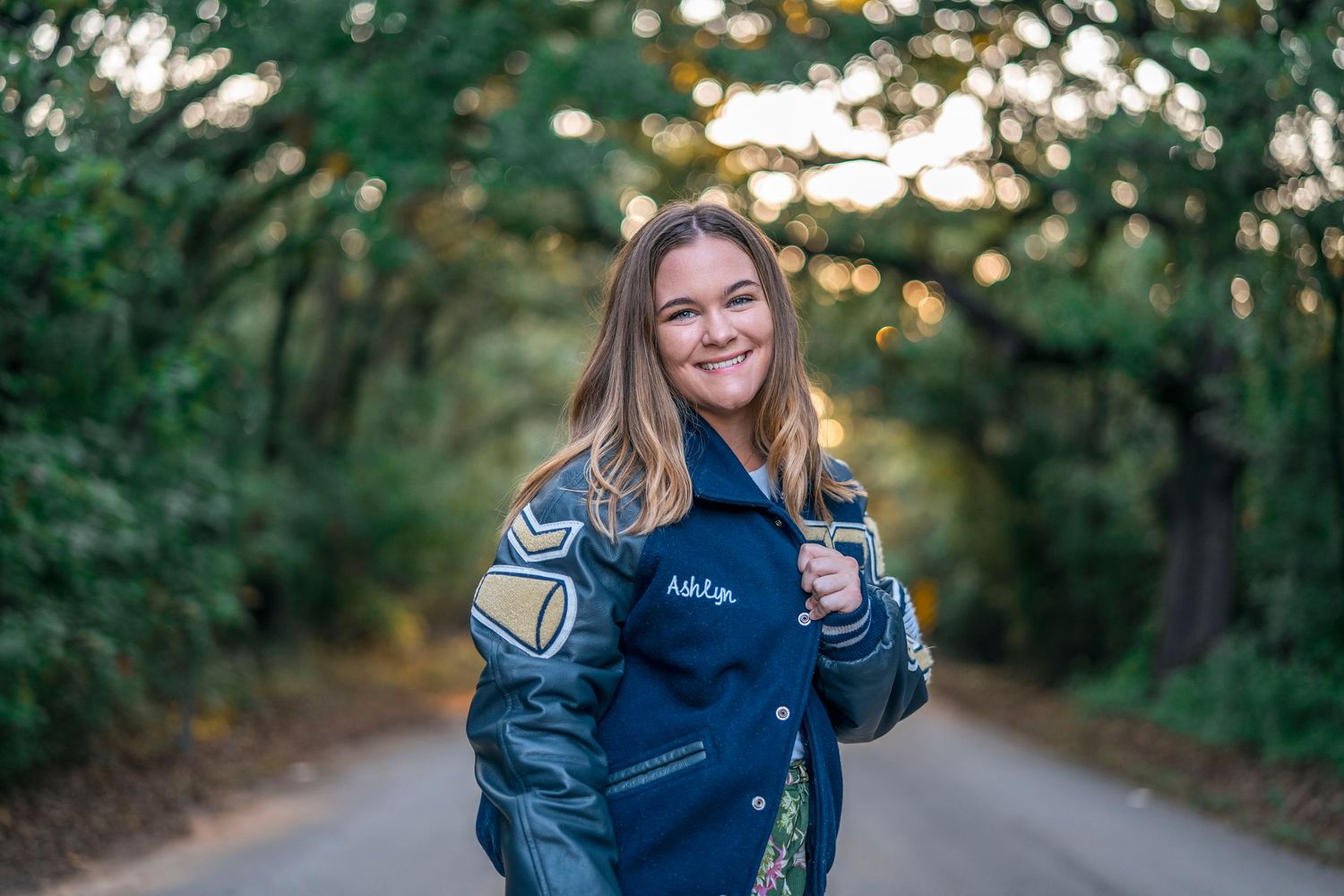 Casual outdoor portraits on a tree-lined path wearing a navy sweater.