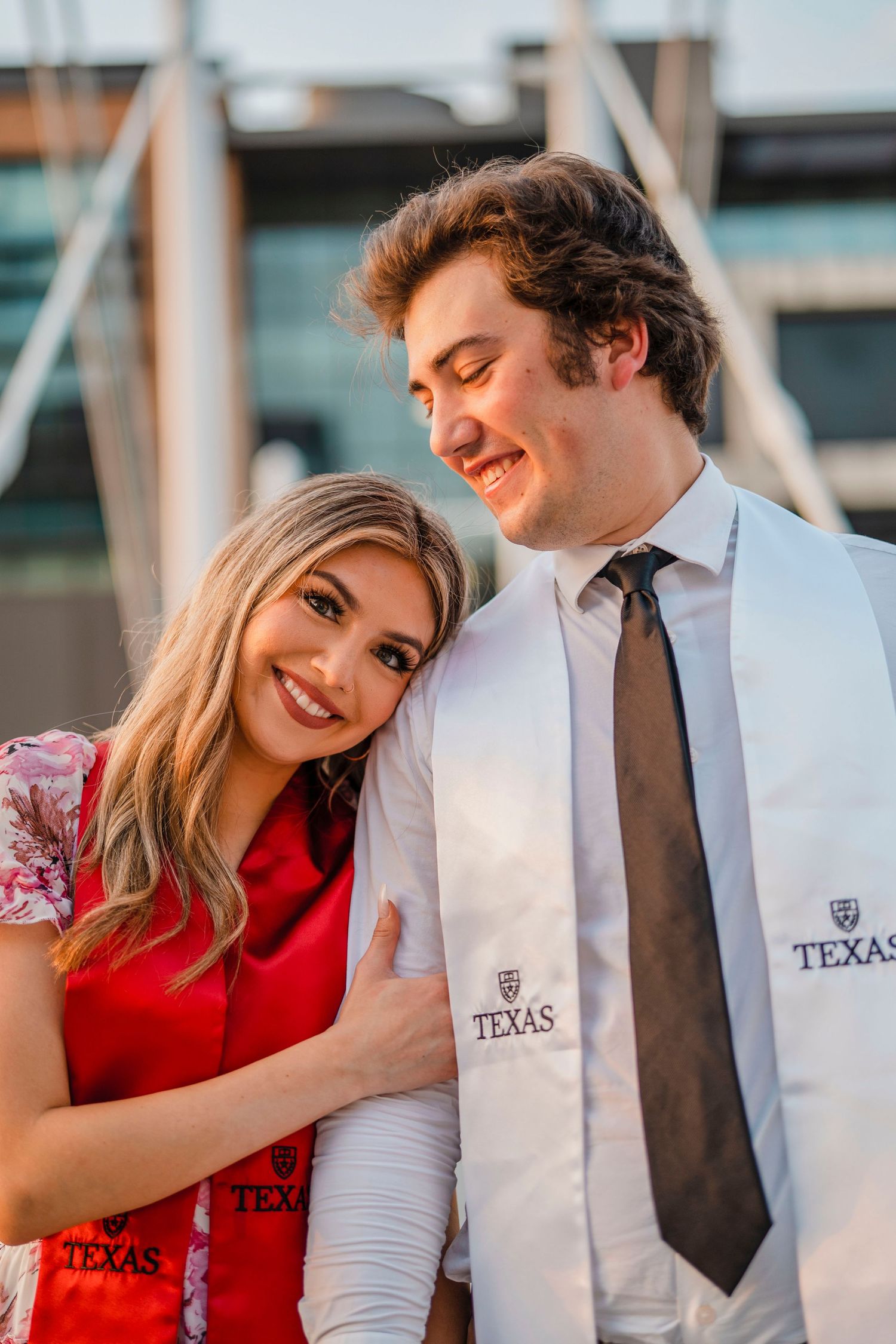 Graduating couple embrace while wearing University of Texas graduation stoles.
