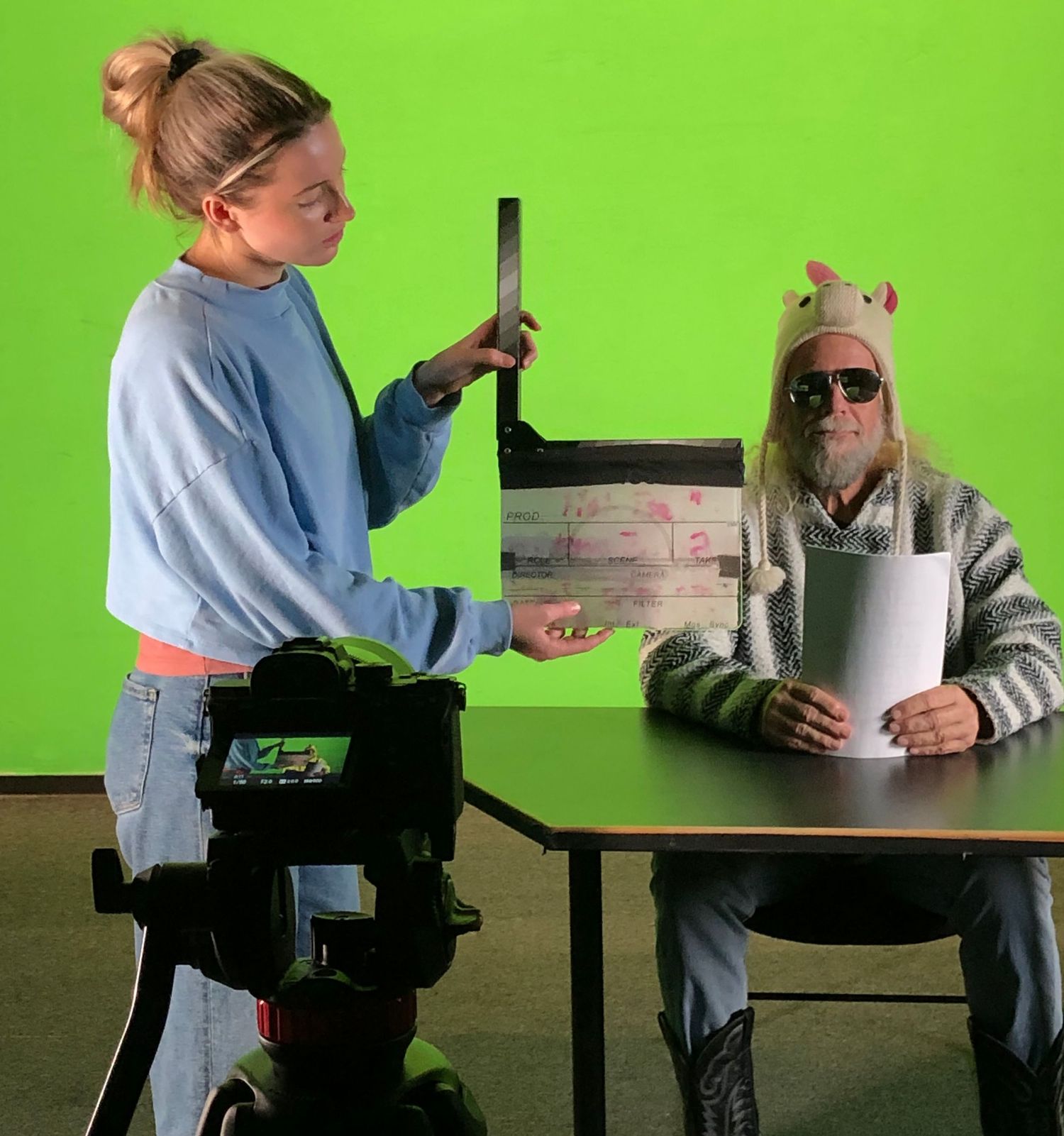 Interview setup with camera equipment against bright green screen background.