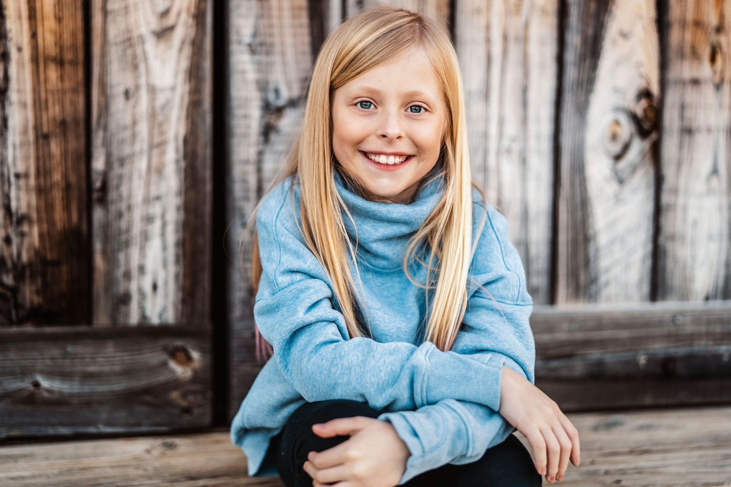 Blue turtleneck sweater portrait series against weathered wooden barn backdrop.