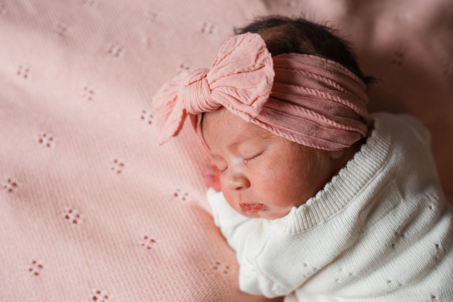 Sleeping newborn baby girl in hospital bassinet with bow during Boise Fresh 48 session