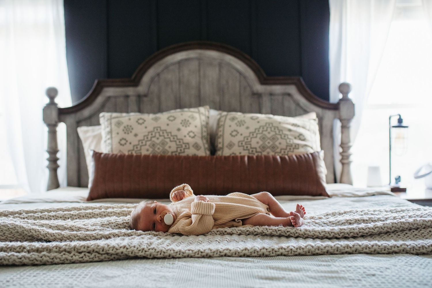 A sleeping baby wearing a onesie lies on a patterned blanket in soft natural light - lifestyle in-home newborn photos Boise
