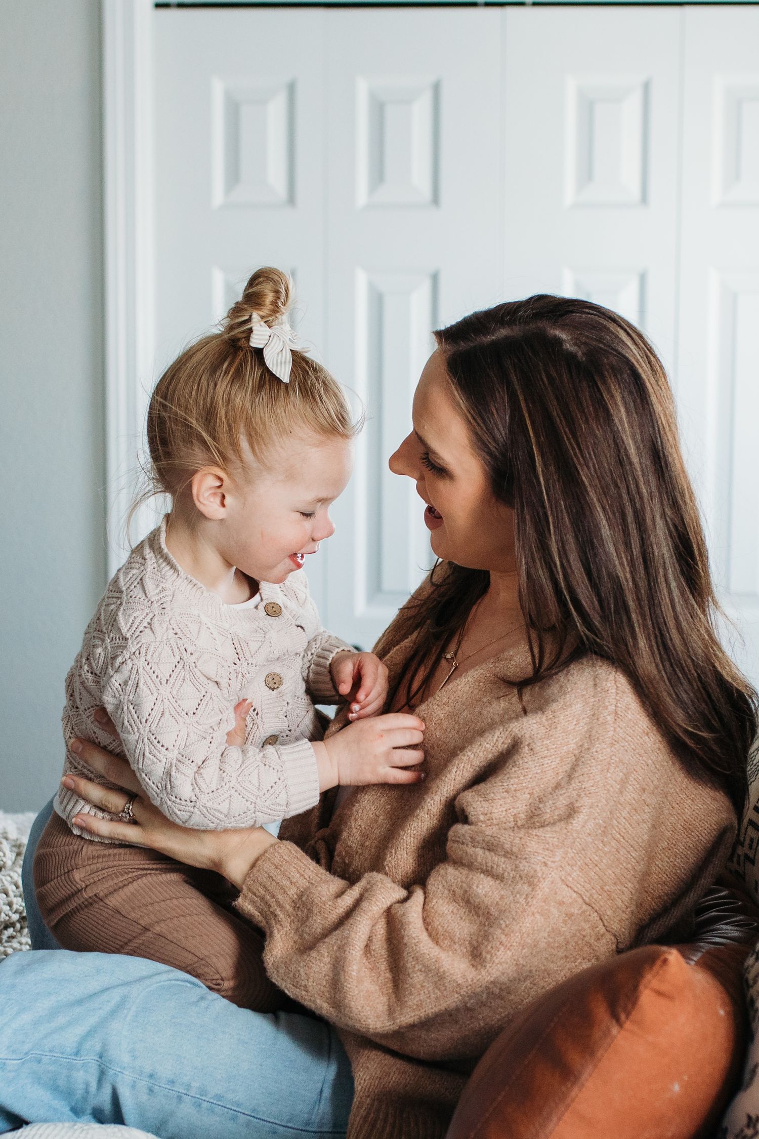 A heartwarming series of candid moments between parent and child sharing laughter while sitting together on a bed -in-home lifestyle family