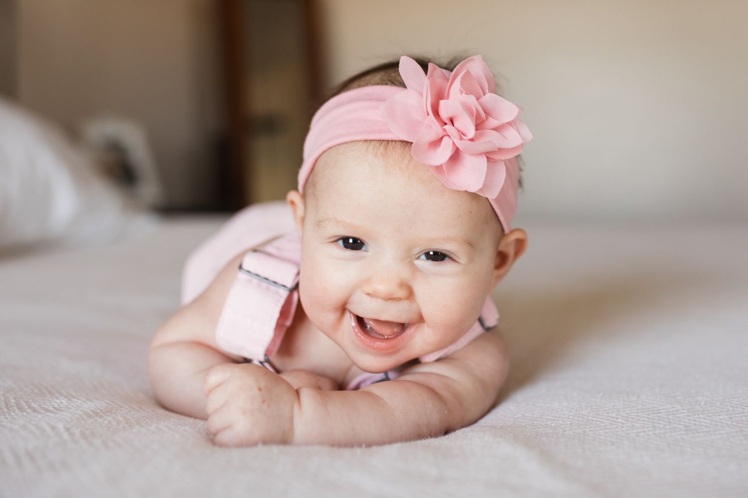 baby portraits on a white blanket with pink floral accessories showing different poses and expressions - 3 month milestone photos Boise