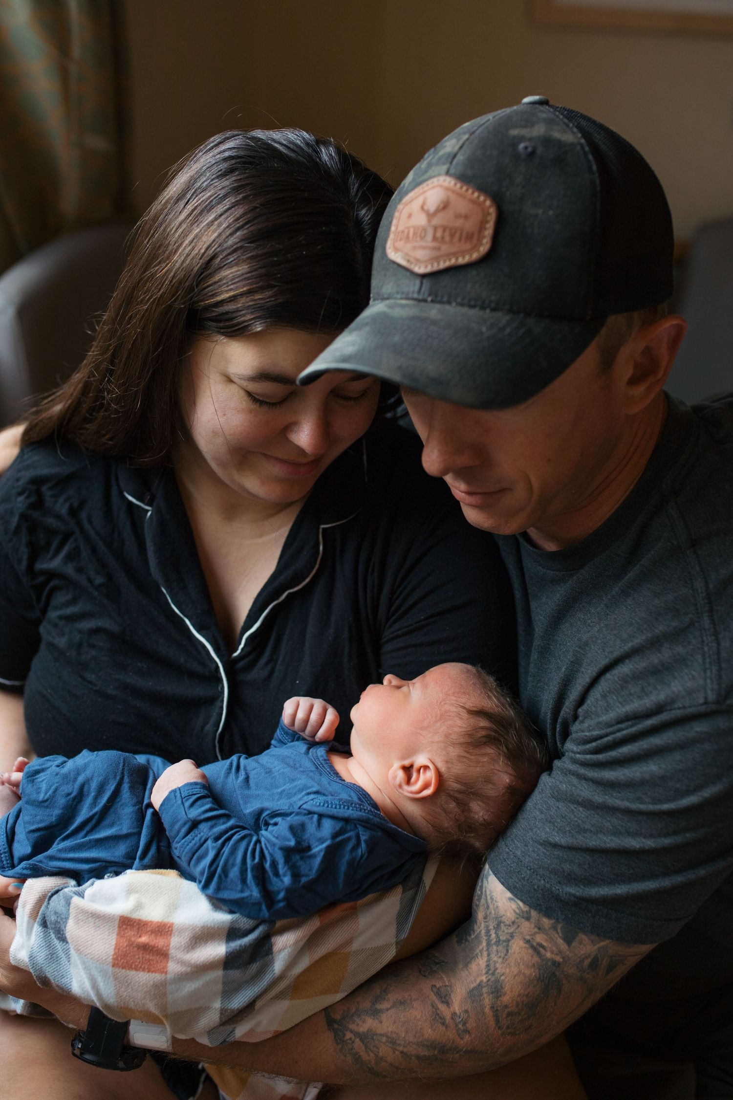 A intimate family moment showing tender interaction between parent and child in dim lighting - Fresh 48 session in Boise, Idaho