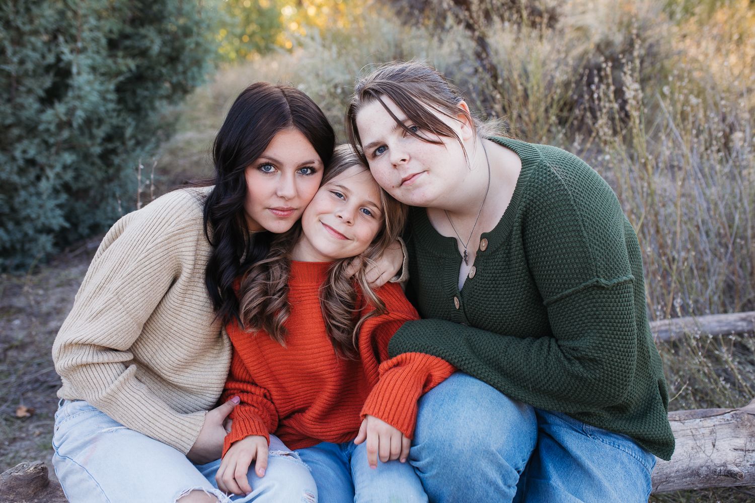 Family wearing coordinating fall outfits poses together on rustic steps during outdoor autumn photoshoot. Boise foothills family photography