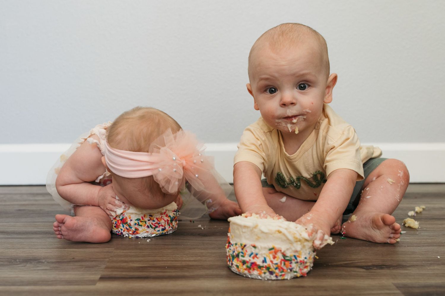 One year old twins enjoying birthday cake during a twin first birthday cake smash session in Kuna, Idaho.