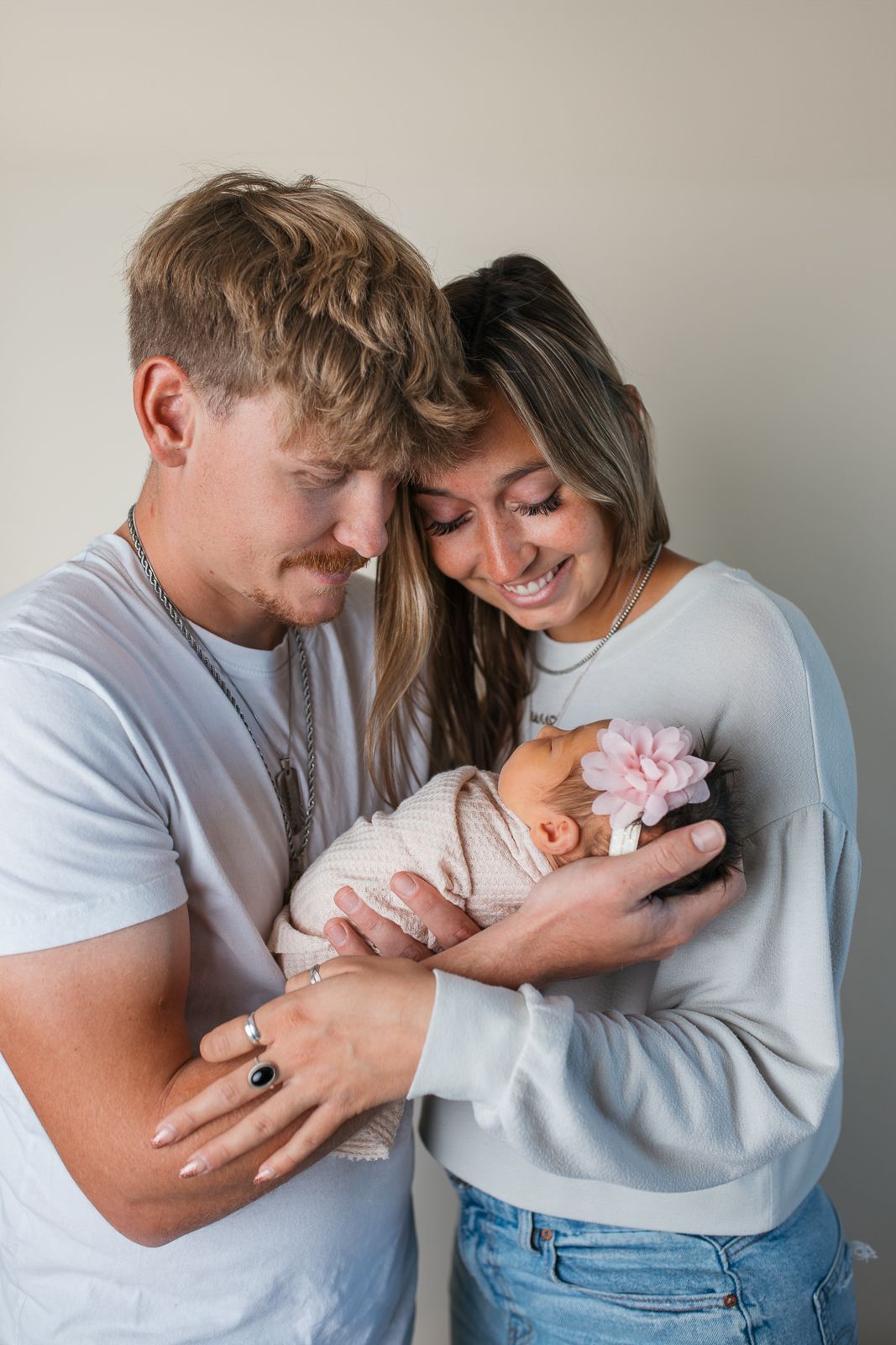 A couple in casual clothing holds and gazes lovingly at their newborn baby in a series of tender moments  studio newborn photography idaho