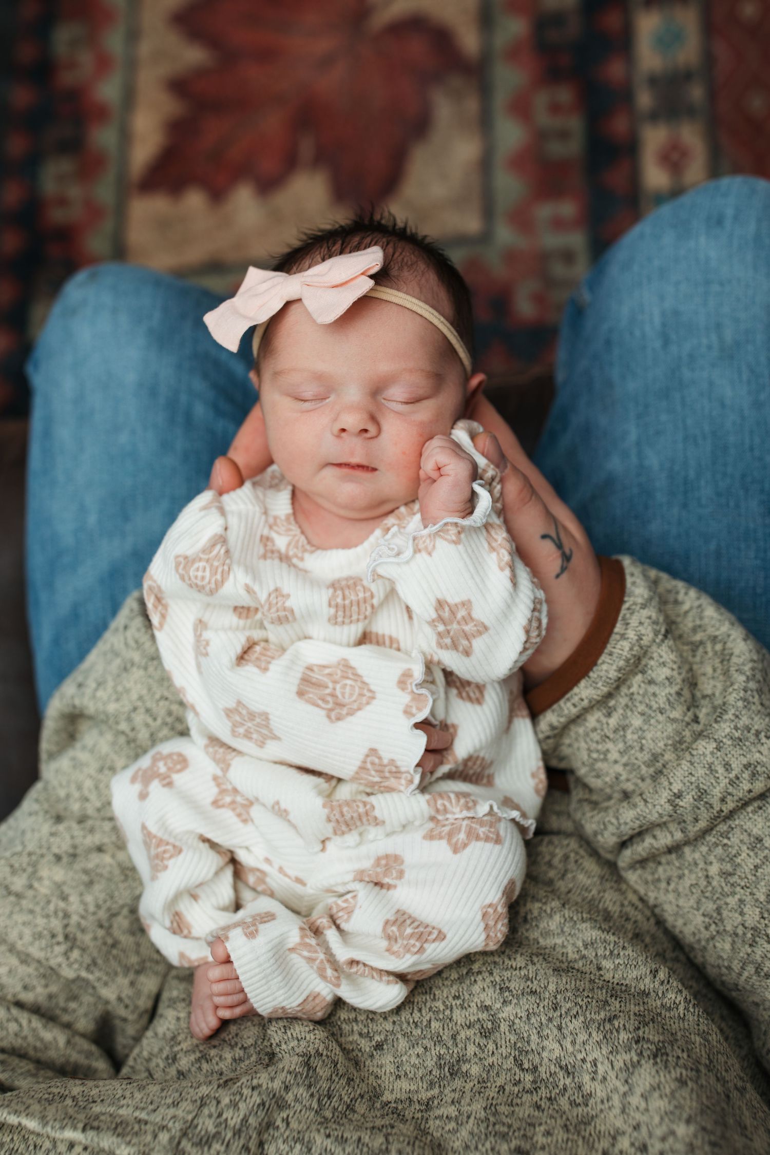 Newborn baby girl resting peacefully on her dad’s lap during an in-home lifestyle newborn session in Middleton, Idaho.