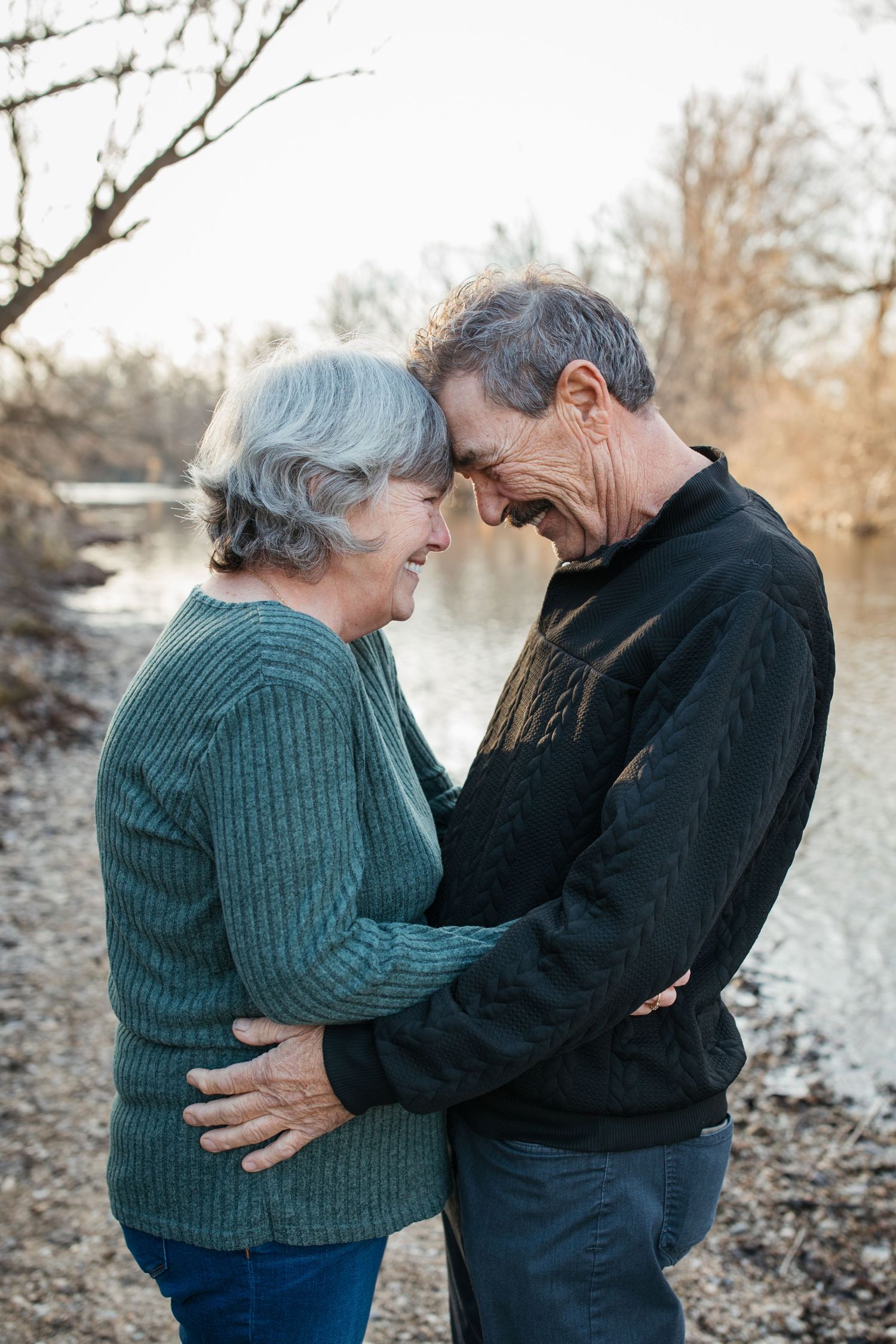 Lifestyle family photography of an older couple hugging by the river, documenting love and connection in Idaho.
