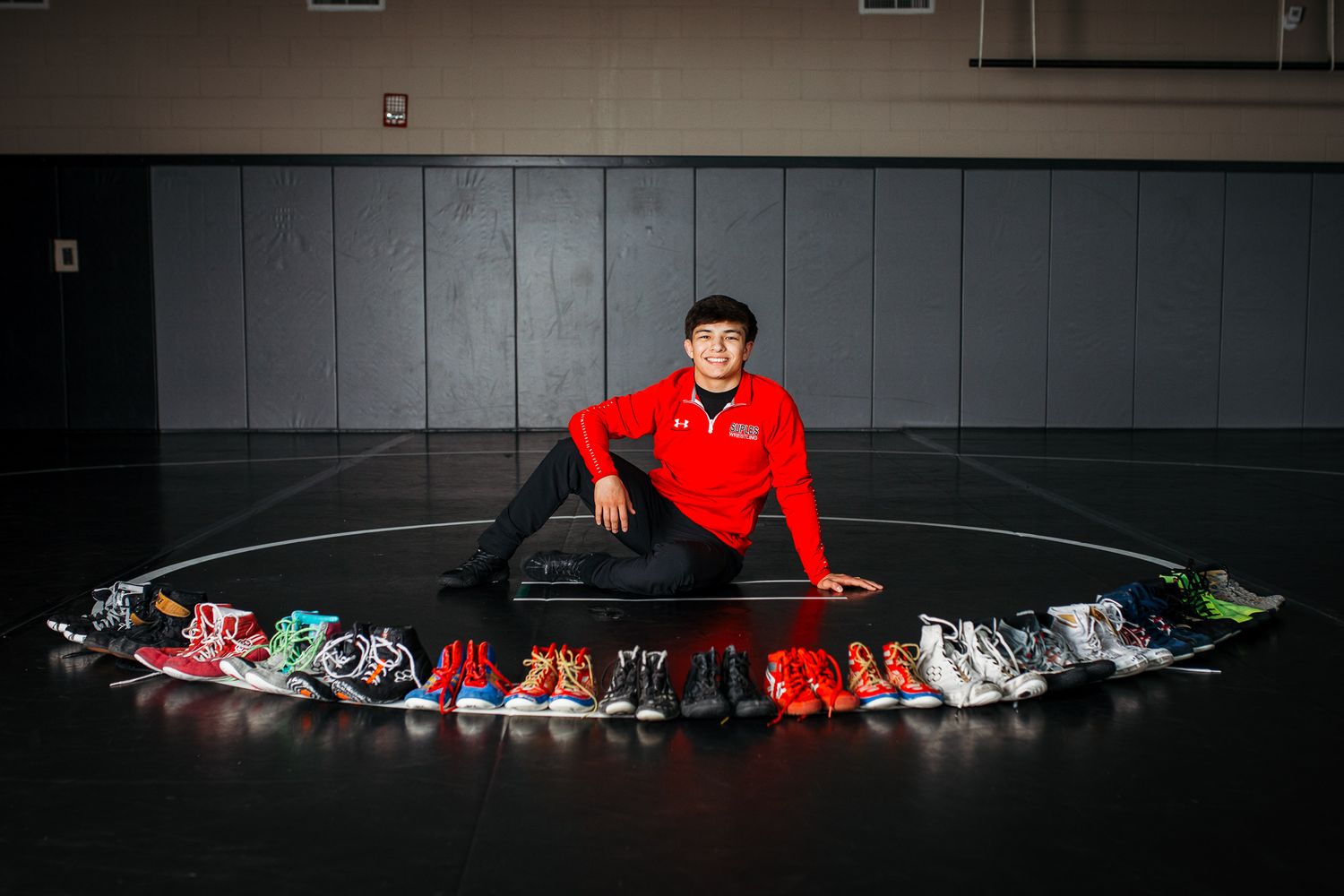 A collection of colorful sneakers arranged in a row on a wrestling mat - Senior photos Boise Idaho