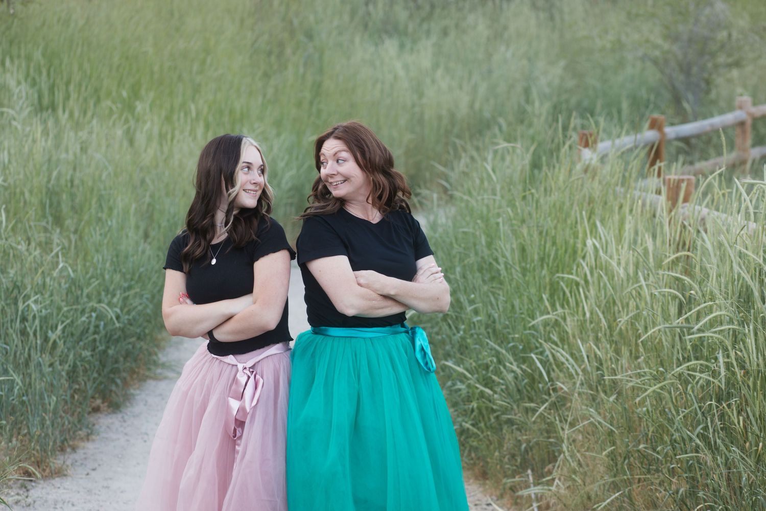 Two sisters smiling at each other during an outdoor summer photography session in the Treasure Valley, Idaho.