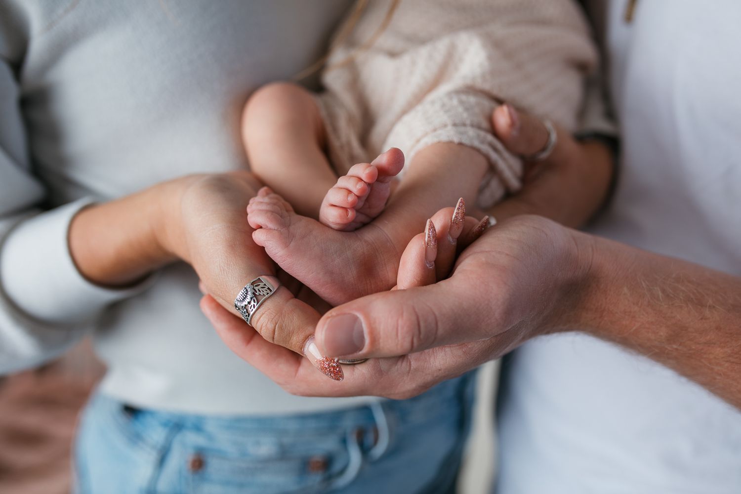 Close-up view of hands holding a small baby's feet against a white background  studio newborn photography Caldwell Idaho