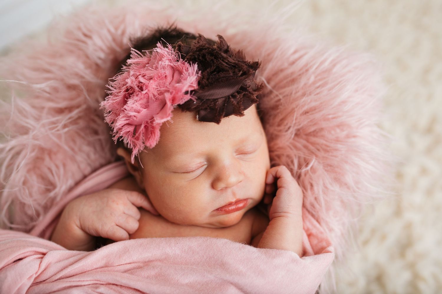 Newborn baby girl sleeping on soft pink fur during a studio newborn photography session in Caldwell, Idaho.