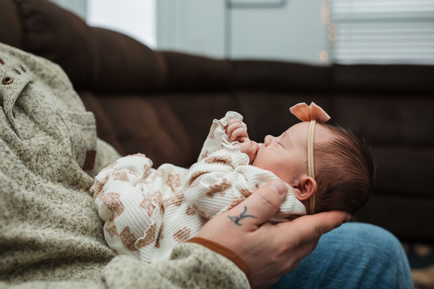 Father cradling his newborn baby girl in his arms during a cozy in-home lifestyle session in Middleton, Idaho.