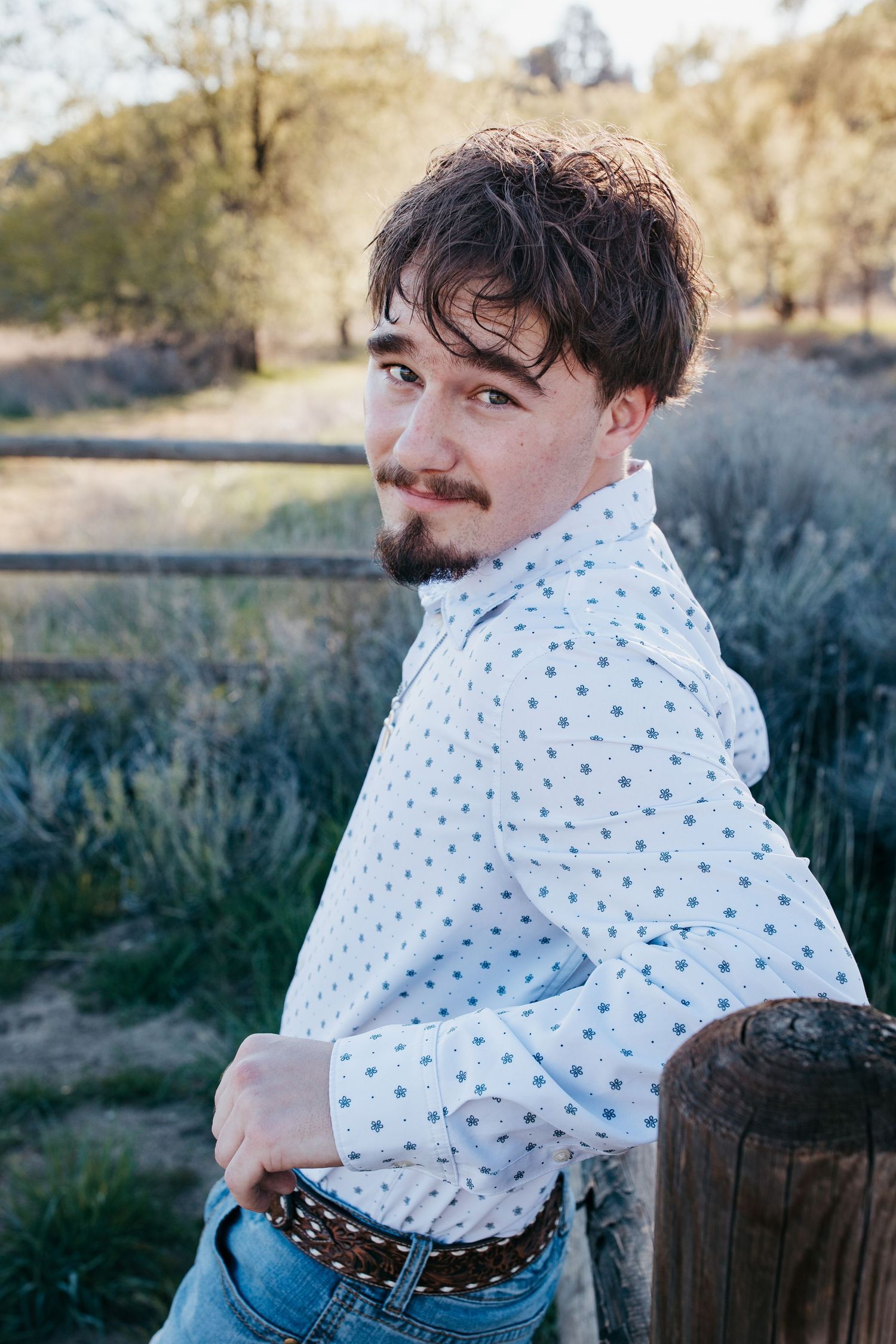 Close up senior portrait of high school boy by wooden fence during Boise Idaho senior photo session