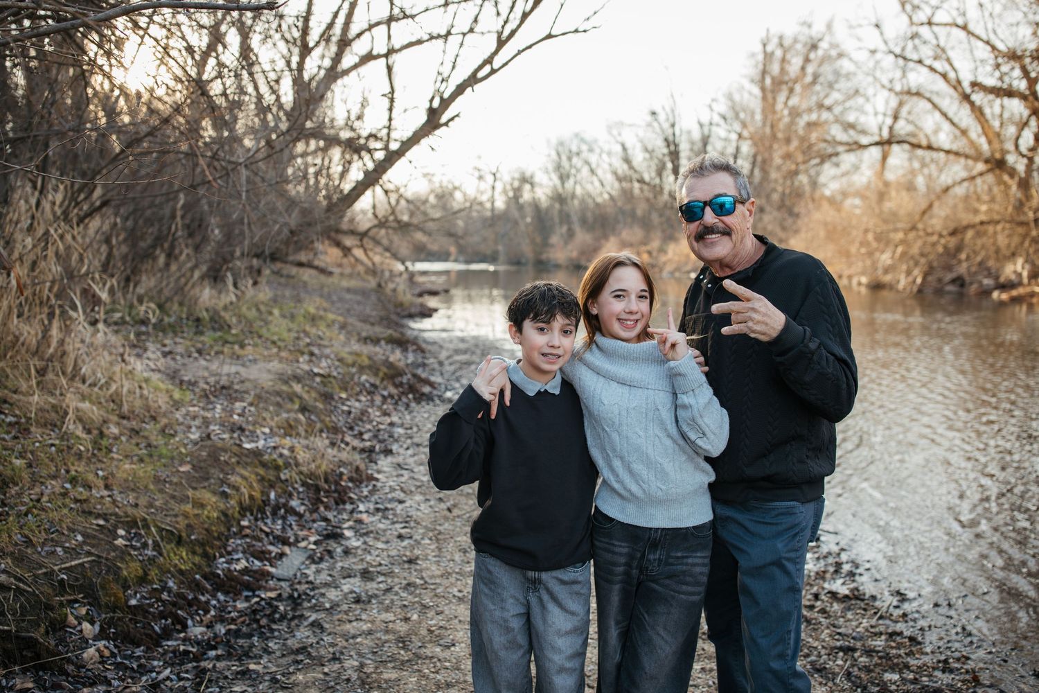 Grandfather smiling with his grandchildren during a lifestyle family photography session by the river in Idaho.