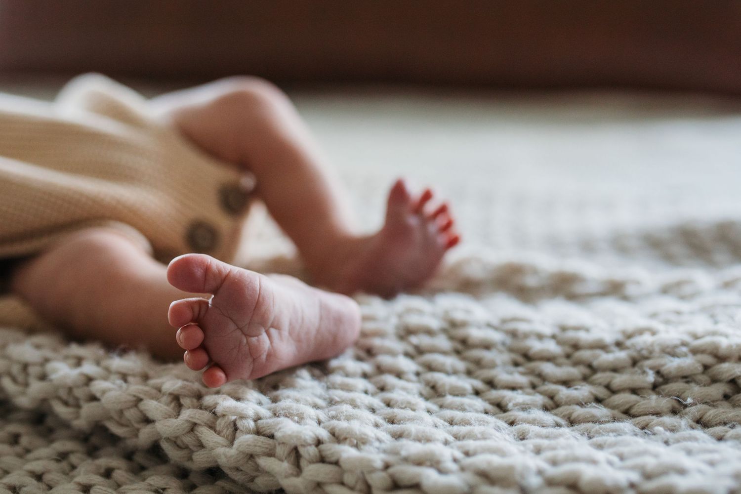 Close-up view of tiny baby feet resting on a soft white knitted blanket texture - lifestyle in-home newborn photos Boise