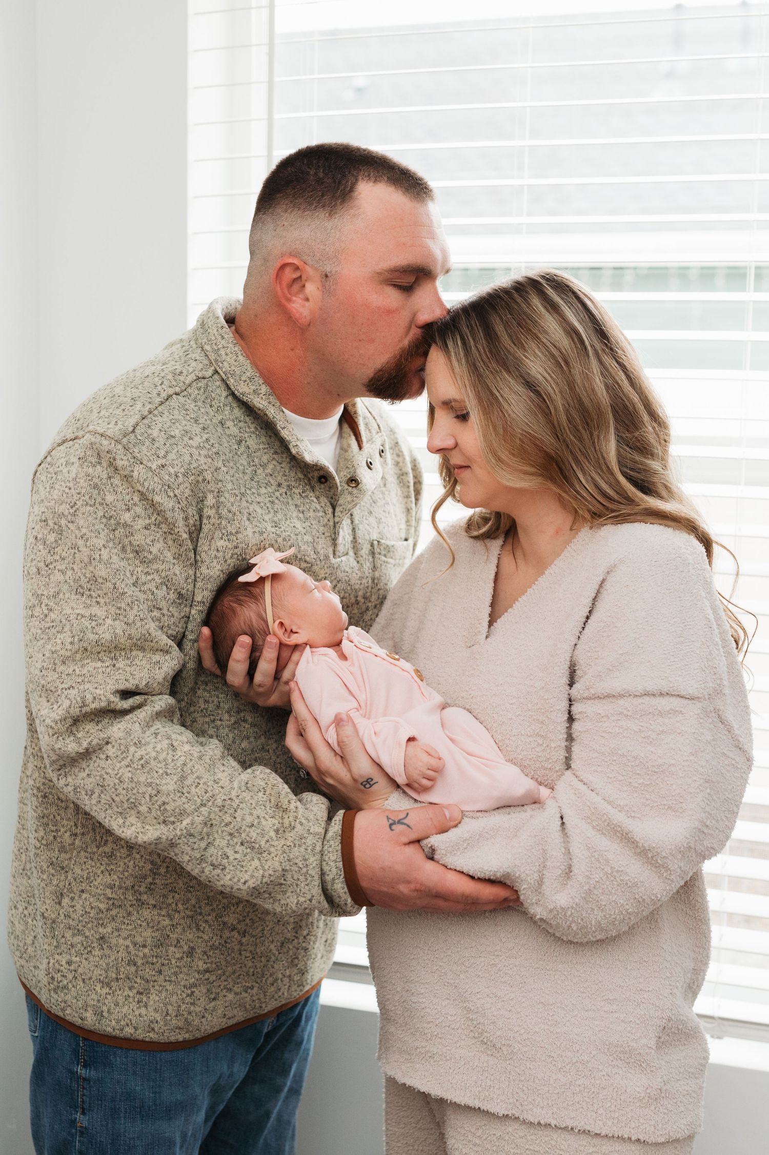 Parents holding their newborn baby during a lifestyle newborn session in Middleton, Idaho, with the father gently kissing the mother’s foreh