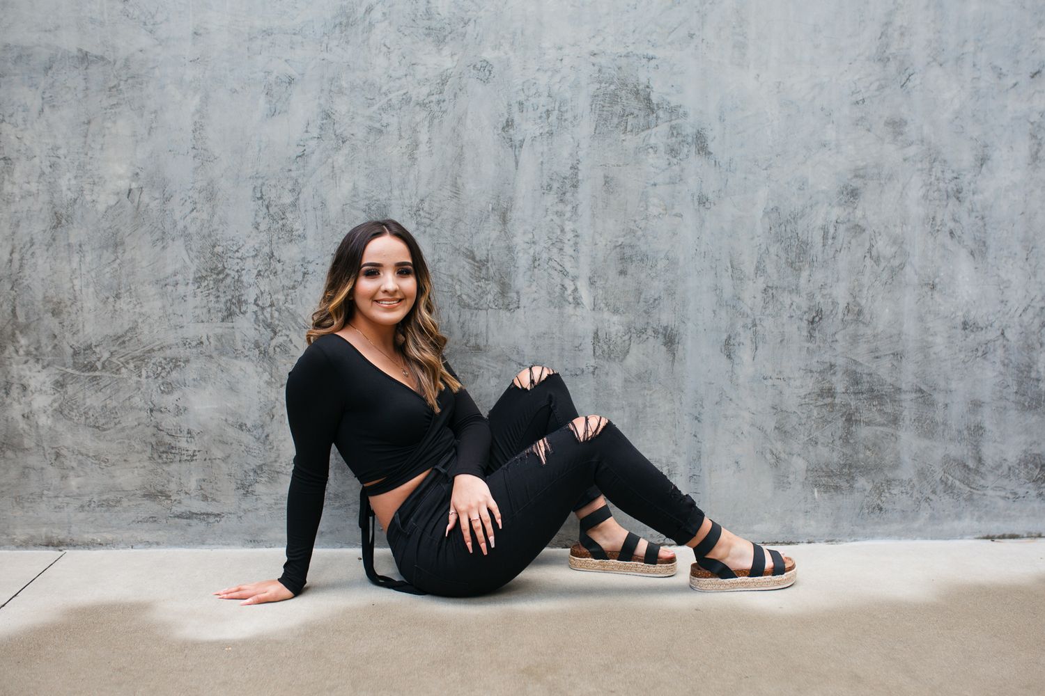 Professional fashion photoshoot with model posing against concrete wall in black outfit and sandals - Senior photos Boise Idaho