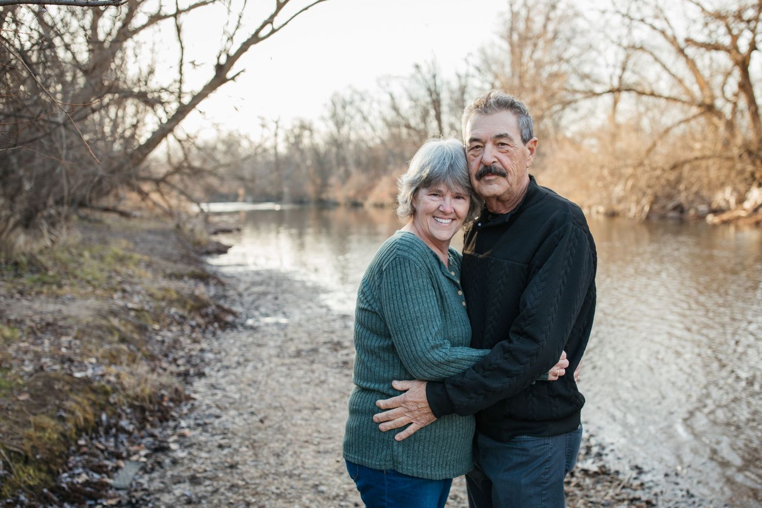 Older couple embracing during a lifestyle family photography session by the river in Idaho, capturing connection and long-term love.