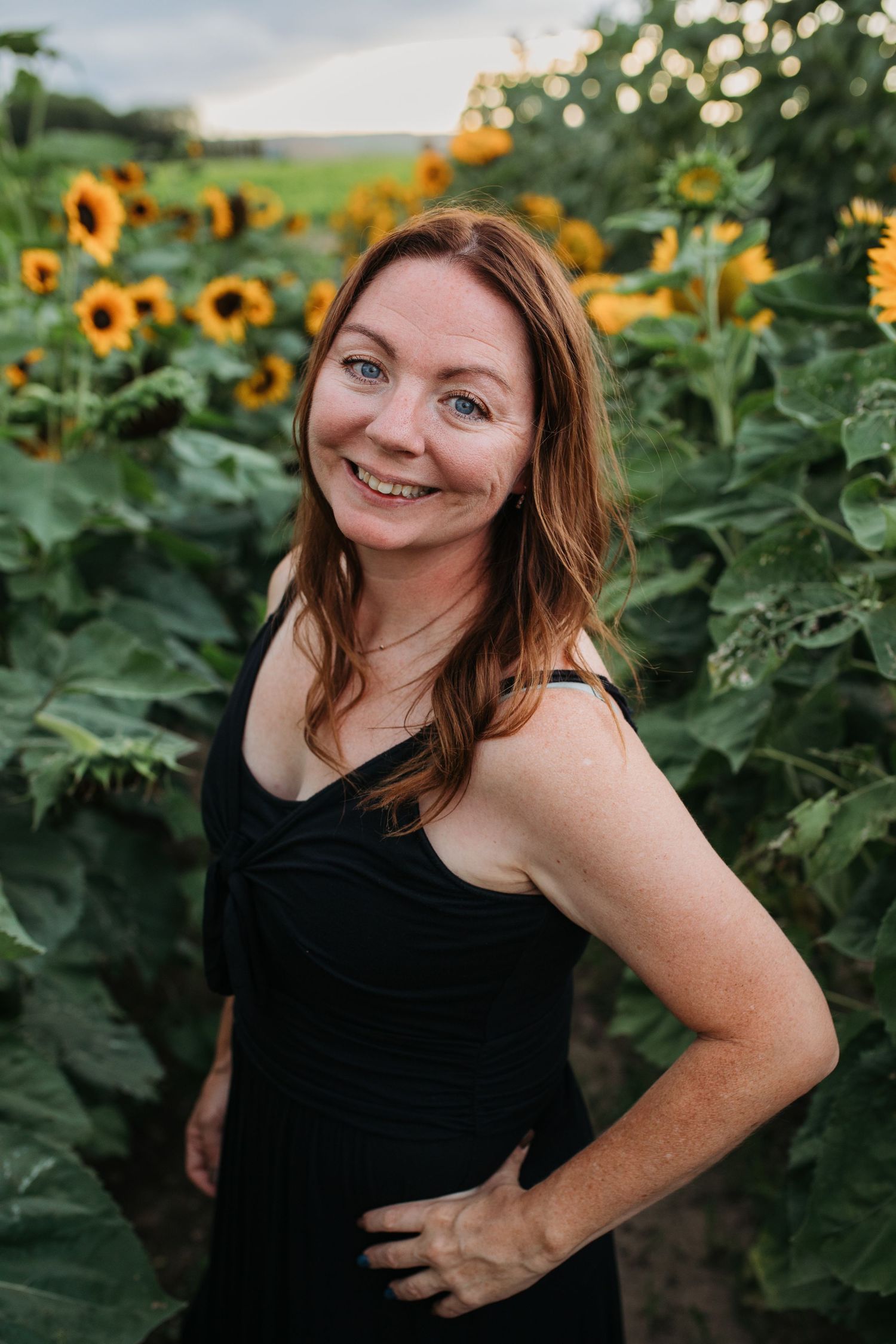 Natural outdoor headshot of woman in sunflower field with relaxed pose, Boise Idaho photographer