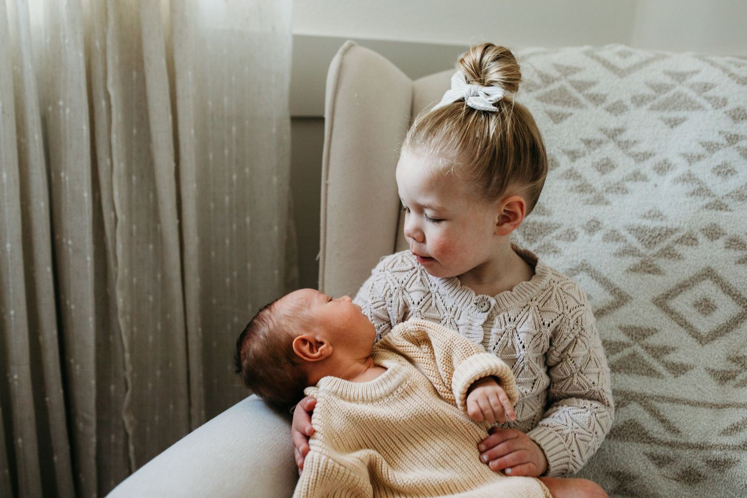 Big sister holding her newborn sibling during an in-home lifestyle newborn session in Boise, Idaho.