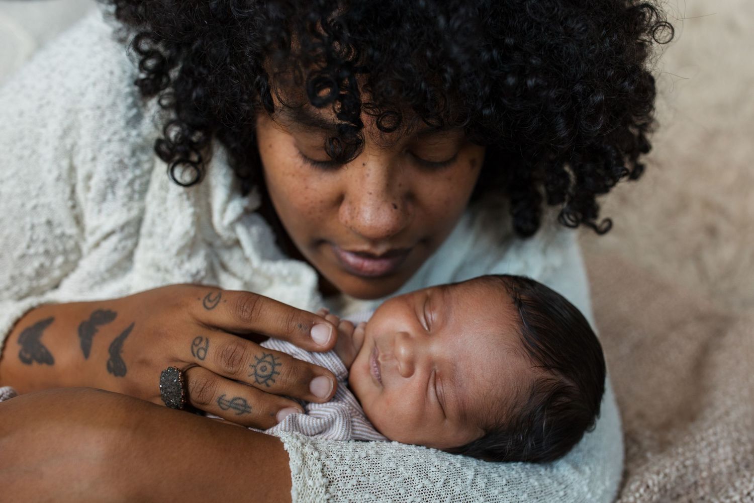Mother looking down at her sleeping newborn baby during a lifestyle newborn photography session in the Treasure Valley.