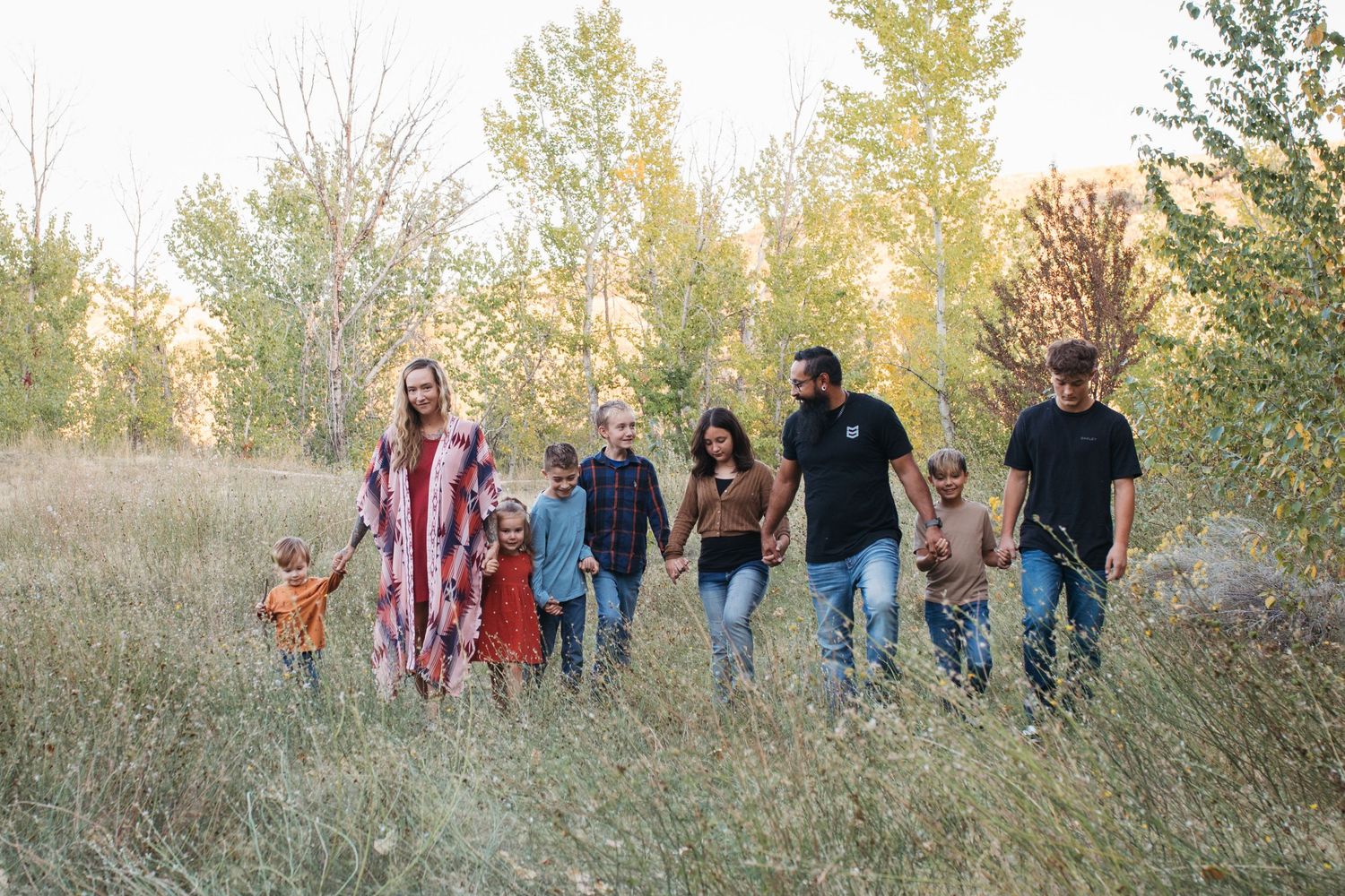 Large family walking together through a Boise park during a fall family photography session in golden evening light.