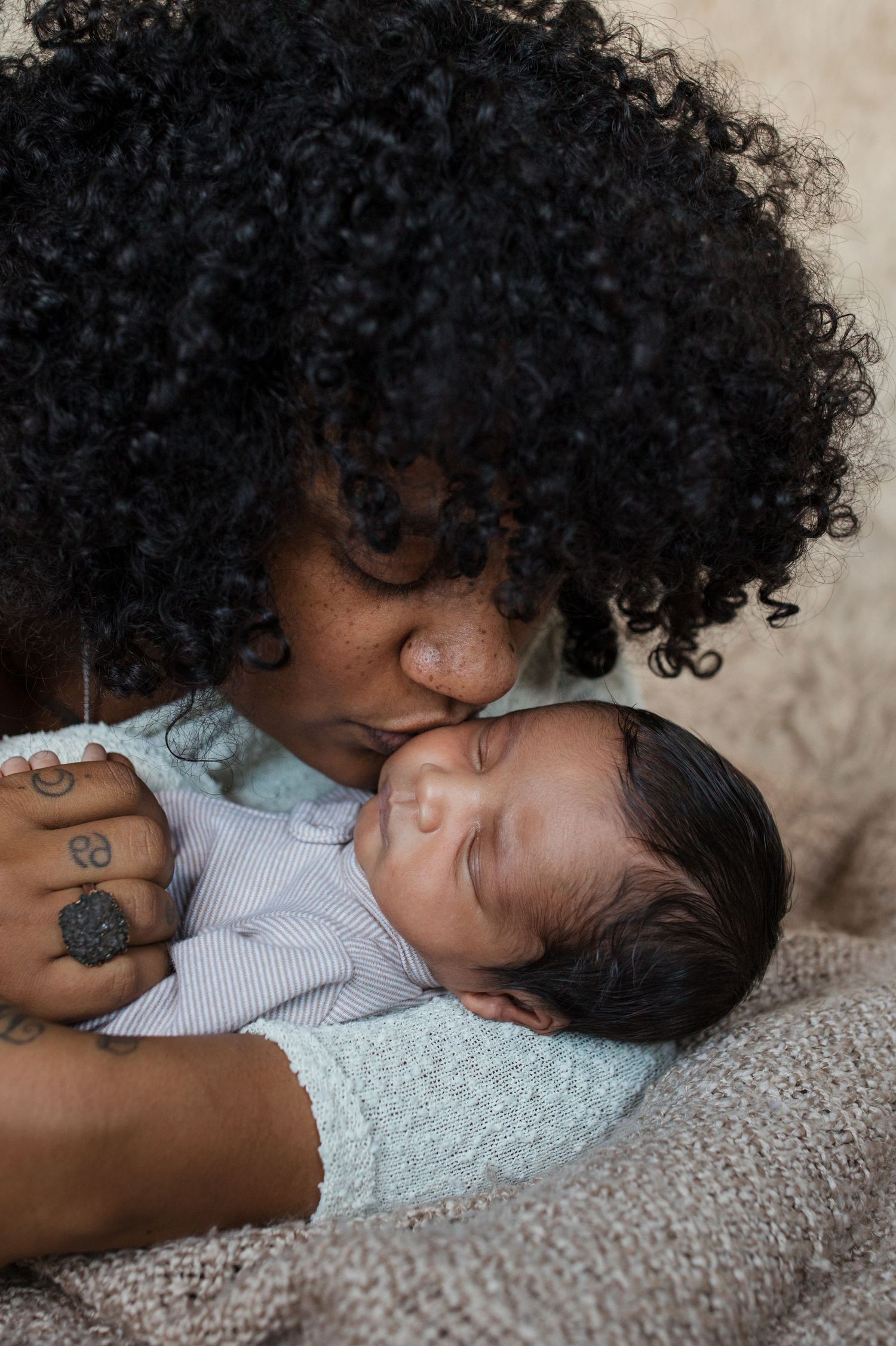 Mother kissing her newborn baby during a lifestyle newborn photography session in the Treasure Valley.