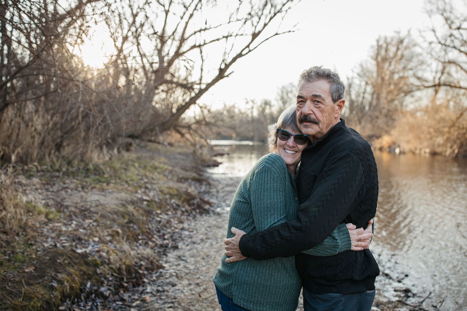 Older couple embracing during a lifestyle family photography session by the river in Idaho, capturing comfort, connection, and love