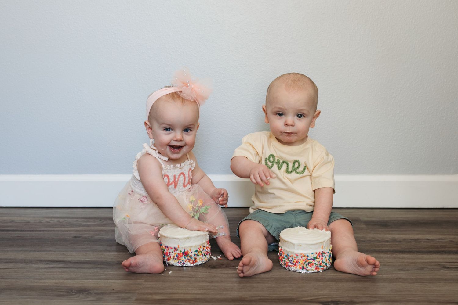Twin first birthday cake smash session in Kuna Idaho featuring one year old twins celebrating their birthday together.