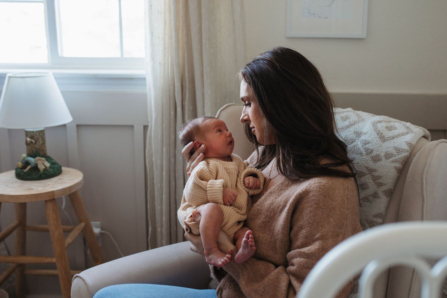 Mother holding her newborn near a window during an in-home lifestyle newborn session in Boise, Idaho.